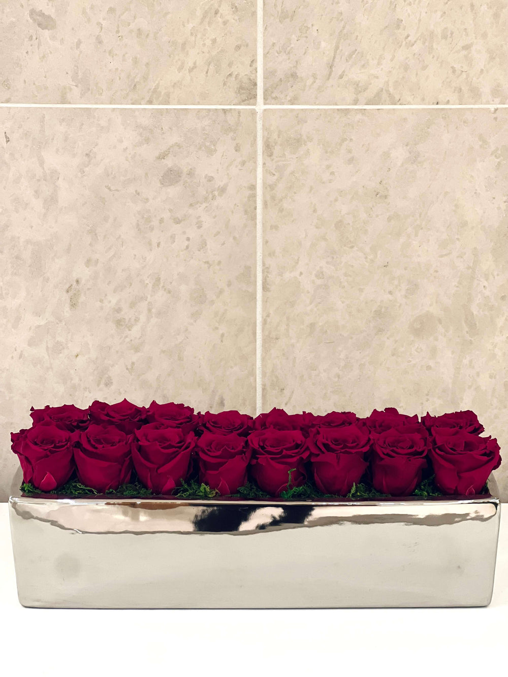 SIXTEEN PRESERVED ROSES IN RECTANGULAR VASE