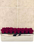 SIXTEEN PRESERVED ROSES IN RECTANGULAR VASE