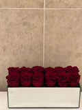 TWELVE PRESERVED ROSES IN RECTANGULAR VASE